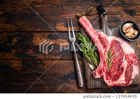 Raw Tomahawk beef steak, fresh black angus ribeye with bone on wooden board. wooden background. top view Raw Tomahawk beef steak, fresh black angus ribeye with bone on wooden board. wooden background. top view 137454439