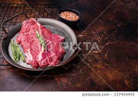Raw hanger tender beef steak, skirt steak with rosemary on steel tray. brown background. top view Raw hanger tender beef steak, skirt steak with rosemary on steel tray. brown background. top view 137454455