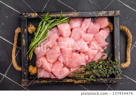 Diced sliced turkey fillet cubes, poultry meat with herbs for cooking. black background. top view 137454474
