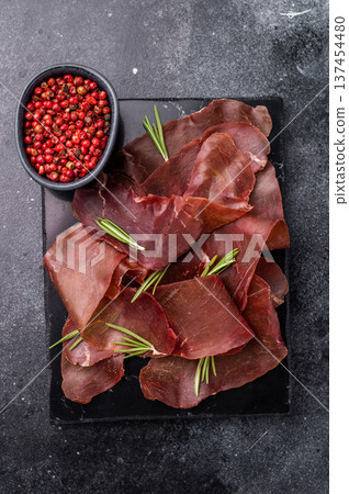 Dried spanish meat slices cecina, spanish tapa. black background. top view Dried spanish meat slices cecina, spanish tapa. black background. top view 137454480
