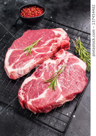Raw pork tender steak, fresh neck meat with herbs on steel rack. black background. top view Raw pork tender steak, fresh neck meat with herbs on steel rack. black background. top view 137454482