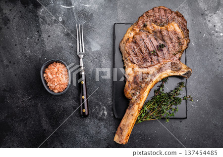 BBQ Grilled Tomahawk beef steak, cooked rib eye with bone on marble board. black background. top view 137454485