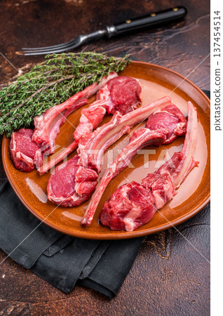 Uncooked lamb chops, fresh mutton meat steaks on a plate. brown background. top view Uncooked lamb chops, fresh mutton meat steaks on a plate. brown background. top view 137454514