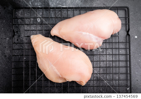 Fresh chicken breasts, beautifully displayed, showcasing their tender texture. Perfect for marinating and cooking your favorite dishes. black background. top view 137454569