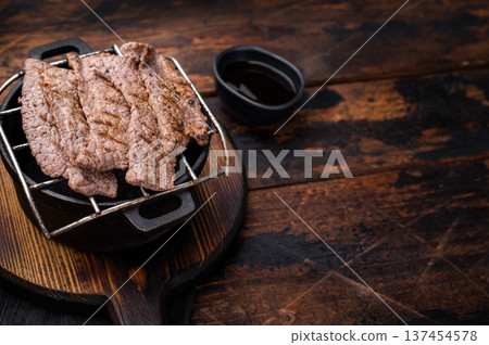 Flavorful yakiniku with juicy wagyu beef slices cooked right at the table. wooden background. top view Flavorful yakiniku with juicy wagyu beef slices cooked right at the table. wooden background. top view 137454578