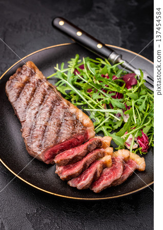 BBQ roast Rump Cap beef steak, Brazilian Picanha with salad on a plate. black background. top view 137454584