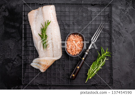 Uncooked Atlantic cod fillet, raw fish ready to be seasoned and transformed into a delicious meal. black background. top view Uncooked Atlantic cod fillet, raw fish ready to be seasoned and transformed into a delicious meal. black background. top view 137454590