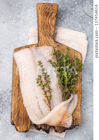 Fresh cod fish fillet, showcasing its delicate texture and pristine color, perfect for grilling or baking. grey background. top view 137454614