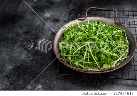Lush rocket greens, showcasing their unique shape and rich color. A delightful addition to any dish. black background. top view 137454615