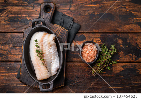 Pristine raw cod fillet, waiting to be marinated and cooked to perfection for a delightful dining experience. wooden background. top view Pristine raw cod fillet, waiting to be marinated and cooked to perfection for a delightful dining experience. wooden background. top view 137454623