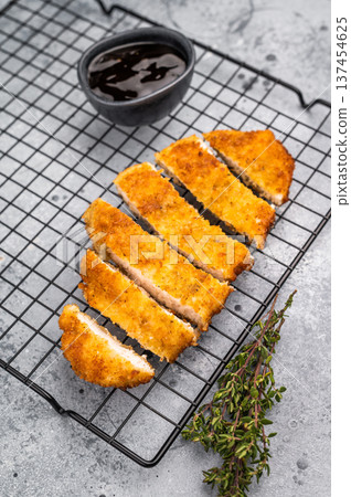 Tender chicken cutlet katsu, coated in crunchy breadcrumbs and fried to perfection. Ideal for a satisfying meal or as a topping for rice. grey background. top view Tender chicken cutlet katsu, coated in crunchy breadcrumbs and fried to perfection. Ideal for a satisfying meal or as a topping for rice. grey background. top view 137454625