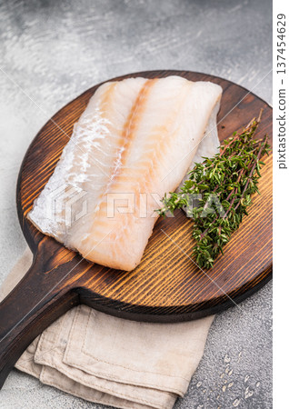 Tender Pacific cod loin, raw fish fillet featuring a light hue and flaky texture, perfect for pan-searing or steaming. grey background. top view Tender Pacific cod loin, raw fish fillet featuring a light hue and flaky texture, perfect for pan-searing or steaming. grey background. top view 137454629
