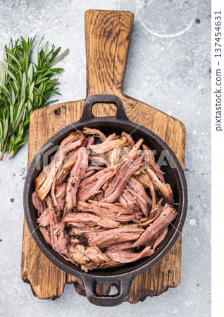Savory pulled beef brisket served in a skillet, dipping creating an appealing and mouthwatering culinary scene. grey background. top view 137454631