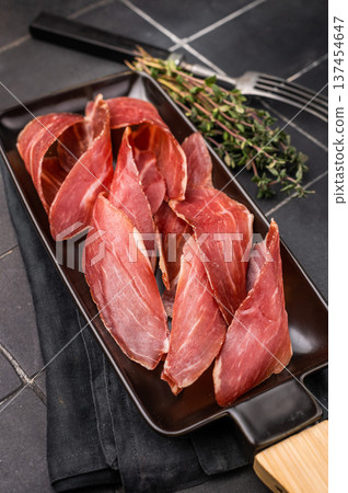 Dry cured and smoked serrano ham, pork meat. black background. top view Dry cured and smoked serrano ham, pork meat. black background. top view 137454647