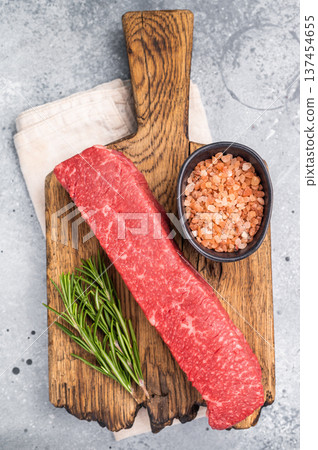 Juicy raw Kobe style beef, renowned for its exceptional flavor and tenderness. Perfect for preparing mouthwatering steaks or sashimi. grey background. top view Juicy raw Kobe style beef, renowned for its exceptional flavor and tenderness. Perfect for preparing mouthwatering steaks or sashimi. grey background. top view 137454655