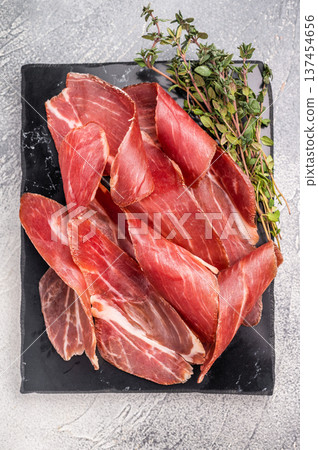 Sliced Speck bacon, Italian cured meat. grey background. top view Sliced Speck bacon, Italian cured meat. grey background. top view 137454656