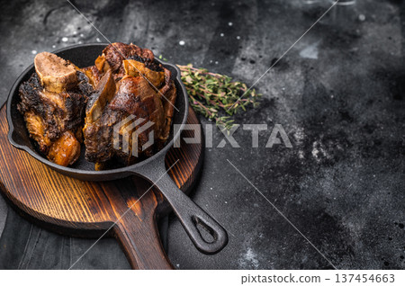 Tender beef short ribs in a pan, seasoned with herbs and spices. Perfect for culinary blogs or restaurant menus that focus on hearty, flavorful meat dishes. black background. top view Tender beef short ribs in a pan, seasoned with herbs and spices. Perfect for culinary blogs or restaurant menus that focus on hearty, flavorful meat dishes. black background. top view 137454663