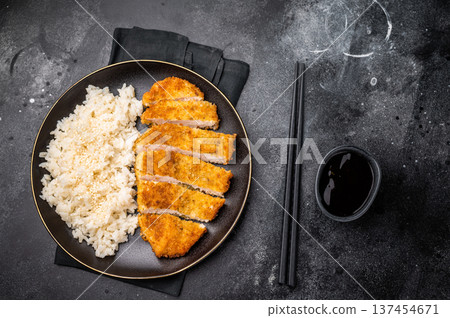 Delicious katsu style dish, featuring a perfectly cooked chicken meat cutlet served alongside steamed rice for a balanced meal. black background. top view 137454671