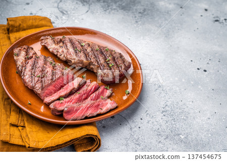 Tender flat iron steak, grilled to enhance its natural flavors and tenderness. grey background. top view Tender flat iron steak, grilled to enhance its natural flavors and tenderness. grey background. top view 137454675