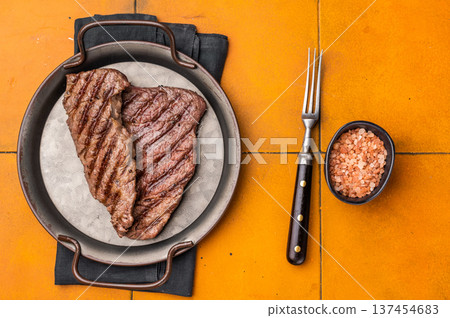 Grilled Denver steak, perfectly seared with beautiful grill marks, showcasing its juicy tenderness and rich flavor. orange background. top view Grilled Denver steak, perfectly seared with beautiful grill marks, showcasing its juicy tenderness and rich flavor. orange background. top view 137454683