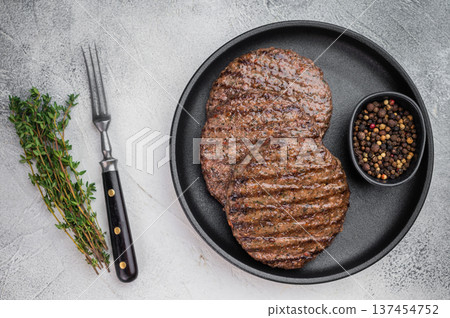 Fried mixed meat patties for burgers made from beef and lamb in skillet with herbs. Light stone background with copy space for menu design. 137454752