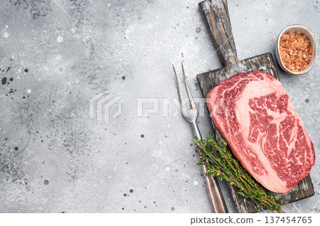 Raw marbled beef rib eye steak entrecote cut on rustic wooden board. Fresh premium butcher meat with rich fat marbling and copy space. 137454765