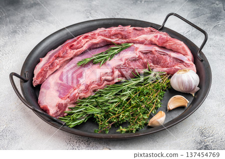 Raw lamb meat belly or breast with herbs and garlic in skillet on light background fatty cut ingredient for barbecue roasting and cooking Raw lamb meat belly or breast with herbs and garlic in skillet on light background fatty cut ingredient for barbecue roasting and cooking 137454769