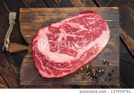 Fresh raw ribeye steak, marbled rib fillet beef cut, gourmet steakhouse meat on rustic wood surface with herbs and copy space 137454791