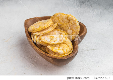 Crispy rice crackers served in rustic wooden bowl. Minimal food composition with clean background. 137454802