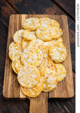 Crispy rice crackers on cutting board on wooden background. Natural snack food in rustic style. Crispy rice crackers on cutting board on wooden background. Natural snack food in rustic style. 137454836