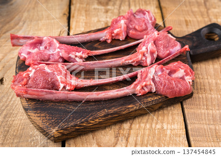 Uncooked lamb cutlets on bone with thyme and vintage fork wooden background butcher style copy space Uncooked lamb cutlets on bone with thyme and vintage fork wooden background butcher style copy space 137454845
