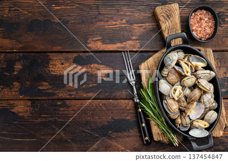Steamed vongole mollusks in black cast iron skillet. Mediterranean seafood composition with shells, rosemary and salt. Steamed vongole mollusks in black cast iron skillet. Mediterranean seafood composition with shells, rosemary and salt. 137454847