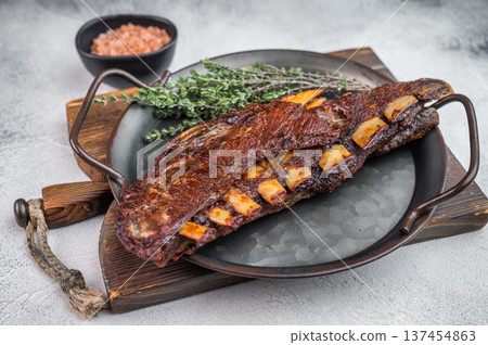 Roasted lamb ribs slab bone in with caramelized surface on rustic dark background gourmet barbecue food Roasted lamb ribs slab bone in with caramelized surface on rustic dark background gourmet barbecue food 137454863