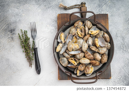 Italian vongole clams arranged in rustic metal pan. Fresh seafood dish with shells on light background, top view. Italian vongole clams arranged in rustic metal pan. Fresh seafood dish with shells on light background, top view. 137454872