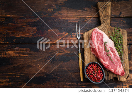 Raw beef chuck eye roll steak on wooden board with thyme and pepper. Marbled beef cut on dark wood background top view copy space.. Raw beef chuck eye roll steak on wooden board with thyme and pepper. Marbled beef cut on dark wood background top view copy space.. 137454874
