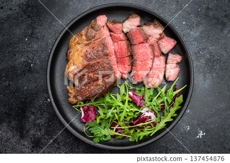 Pan fried beef chuckeye roll steak sliced and served with leafy greens. Gourmet beef dish with copy space top view. 137454876