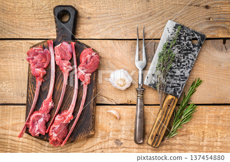 Uncooked lamb cutlets on bone with thyme and vintage fork wooden background butcher style copy space 137454880