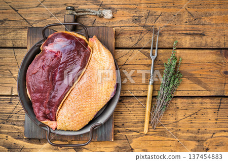 Raw duck breast with skin in pan on wooden background with thyme. Gamebird poultry game meat ingredient top view with copy space.. Raw duck breast with skin in pan on wooden background with thyme. Gamebird poultry game meat ingredient top view with copy space.. 137454883