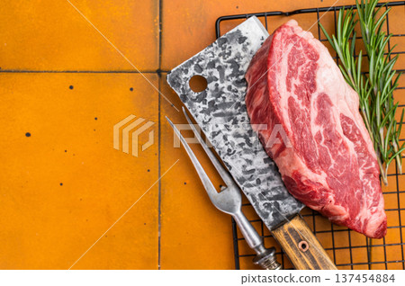 Fresh raw beef chuck eye roll steak on metal rack with butcher tools and herbs. Premium marbled beef meat for cooking. 137454884