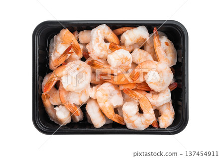Frozen cooked shrimp with tails in black tray from super market isolated on white background. Icy seafood protein ingredient closeup. Frozen cooked shrimp with tails in black tray from super market isolated on white background. Icy seafood protein ingredient closeup. 137454911