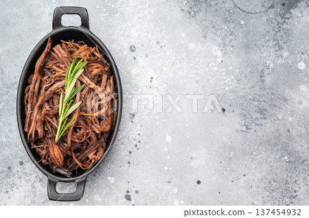 Slow cooked shredded brisket, juicy BBQ beef in rustic pan, top view food photo with copyspace for menu or recipe. 137454932