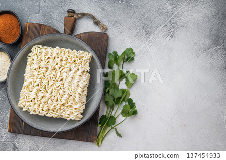 Uncooked dehydrated ramen noodles served in bowl on bright textured backdrop pantry staple fast budget meal ingredient 137454933