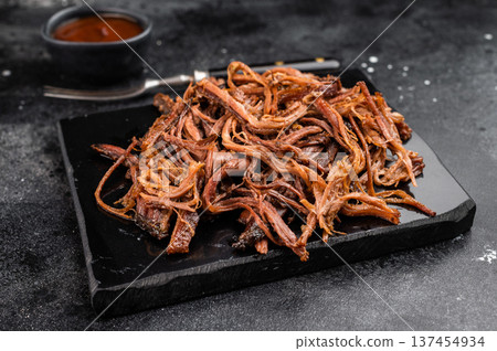Smoked shredded brisket meat on black stone tray, dried beef strips snack, barbecue style protein food. 137454934