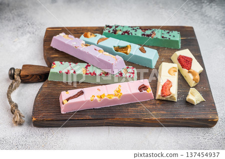 Variety of handmade gourmet chocolate with berry and nut toppings arranged on wooden cutting boards minimal flat lay 137454937
