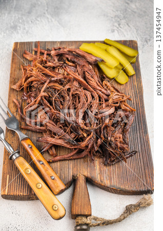 Slow cooked shredded beef brisket, smoky barbecue meat ready to serve, comfort food platter with sauce and pickles. Slow cooked shredded beef brisket, smoky barbecue meat ready to serve, comfort food platter with sauce and pickles. 137454947