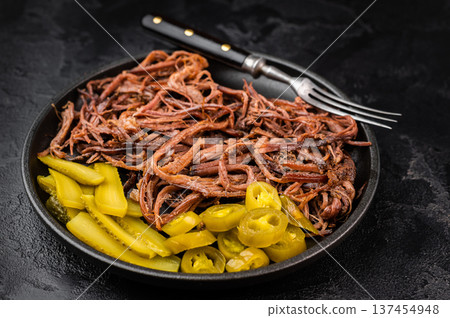 Pulled beef brisket with barbecue sauce, pickles and jalapeno in skillet on dark background, top view with copy space.. Pulled beef brisket with barbecue sauce, pickles and jalapeno in skillet on dark background, top view with copy space.. 137454948