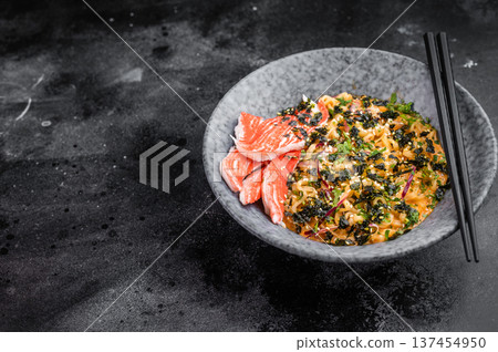 Bowl of spicy seafood ramen noodles with crab sticks nori and sesame on dark background Asian comfort food top view 137454950