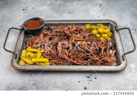 Pulled beef brisket with barbecue sauce, jalapeno and pickles on metal tray, top view with copy space on light background. 137454958