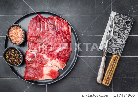 Top view of raw marbled beef brisket on plate with salt and pepper, clean dark background for steakhouse menu Top view of raw marbled beef brisket on plate with salt and pepper, clean dark background for steakhouse menu 137454960
