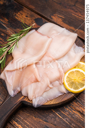 Freshly caught raw squid with glistening skin, perfect for grilling or frying to create mouthwatering dishes. wooden background. top view 137454975